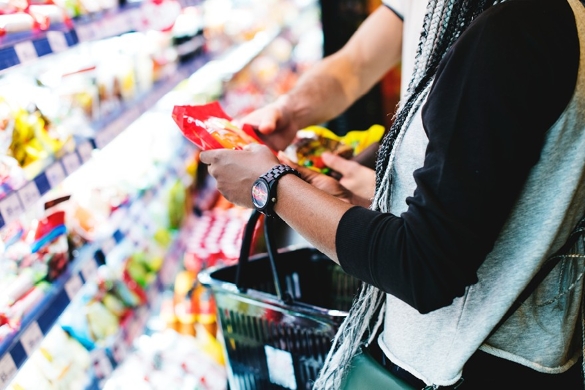 Shopper examines packaged food ingredient labels in a grocery store, highlighting artificial food dye awareness.
