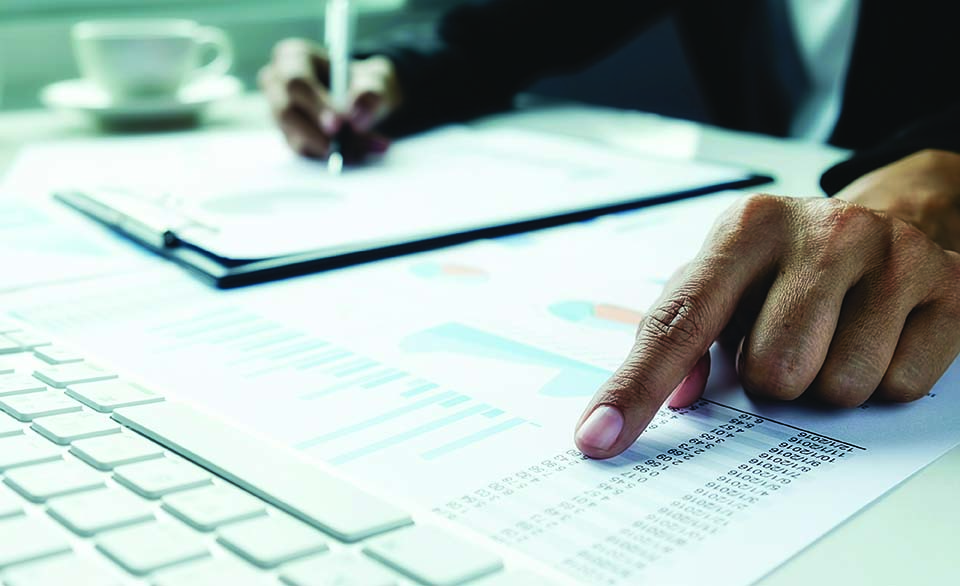 Professional reviewing financial reports, charts, and revenue data to support economic development planning and funding decisions.