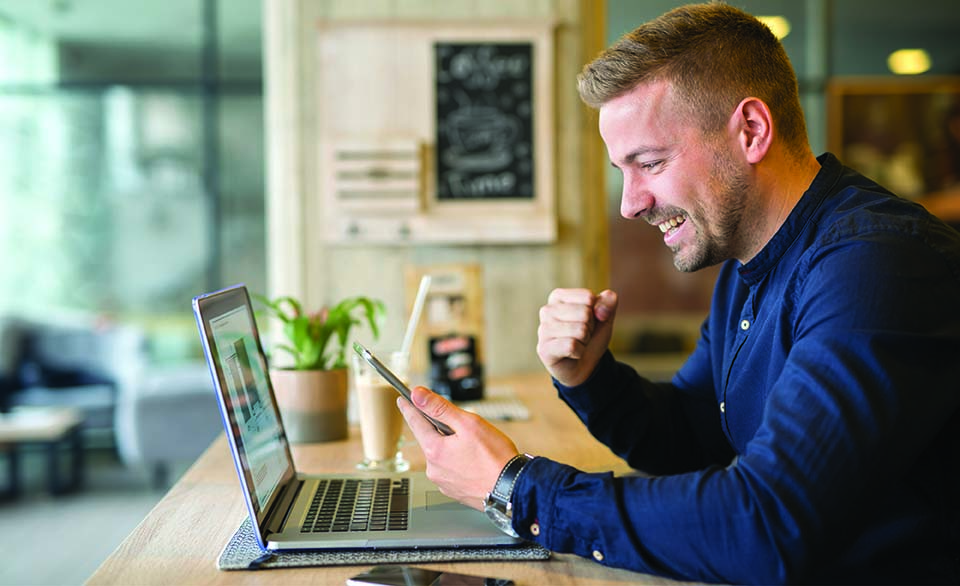 Entrepreneur celebrating success while working on a laptop, highlighting business growth and startup support programs.