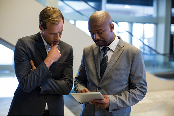 Two professionals reviewing information on a tablet in an office setting.
